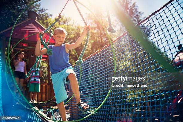 kleiner junge wandern in modernen seile kurs spielplatz - hochseilgarten stock-fotos und bilder