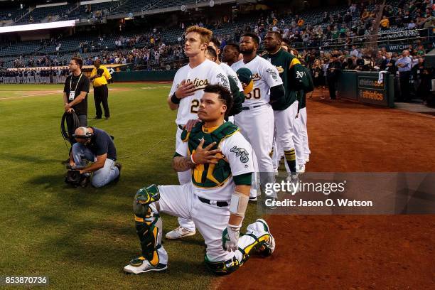 Bruce Maxwell of the Oakland Athletics kneels during the national anthem in front of teammate Mark Canha before the game against the Seattle Mariners...