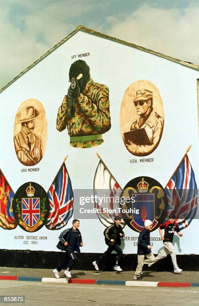 Children run past an Ulster Freedom Fighters Loyalist mural April 16, 2001 in an Protestant Loyalist neighborhood on the Lower Shankill Road in...