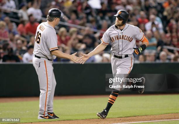 Hunter Pence of the San Francisco Giants is congratulated by third base coach Phil Nevin after hitting a solo home run against the Arizona...