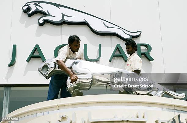 Asian migrant labourers polish a gleaming logo for a luxury car brand at a dealership on May 1, 2006 in Dubai, United Arab Emirates. Dubai is a place...