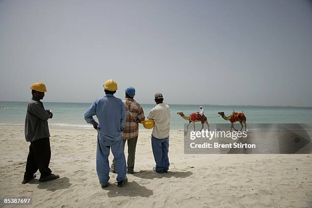 Migrant labourers take a break at a beach popular with tourists in the Dubai Marina area on May 1, 2006 in Dubai, United Arab Emirates. The workers...