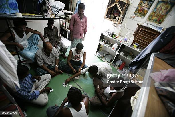 Abandoned construction labourers play cards in a makeshift labour camp on May 1, 2006 in Sharjah, United Arab Emirates. The labourers were left...