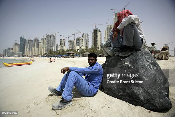 Migrant labourers take a break at a beach popular with tourists in the Dubai Marina area on May 1, 2006 in Dubai, United Arab Emirates. The workers...