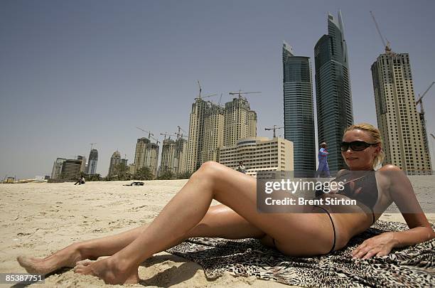 Migrant labourers stare at a sunbathing tourist as they take a break on a beach adjacent to the massive construction site which comprises much of the...