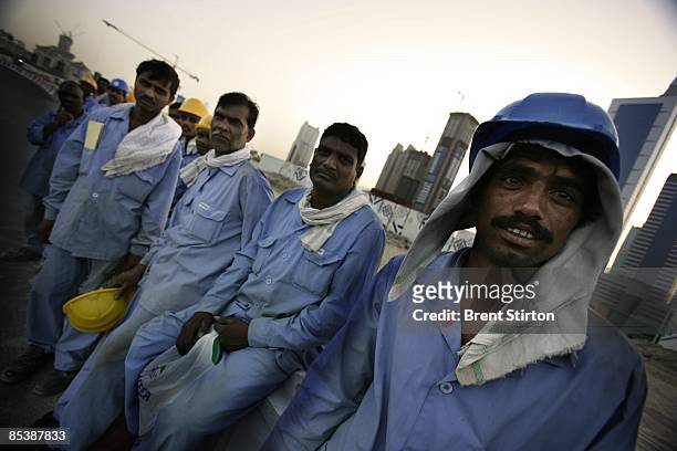 Migrant construction labourers working in Dubai line up to board a bus which will take them back to their labour camp for the night on May 1, 2006 in...