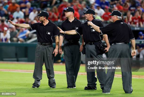 The umpires gesture towards starting pitcher Collin McHugh of the Houston Astros during the second inning of a baseball game against the Texas...