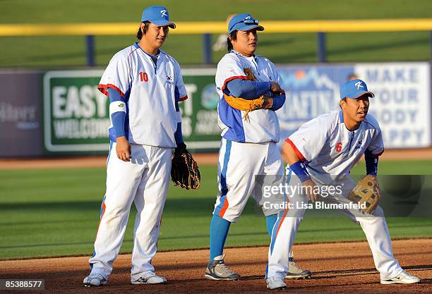 Dae Ho Lee, Tae Kyun Kim and Bum Ho Lee of Korea warm up before an exhibition game against the San Diego Padres at Peoria Stadium March 11, 2009 in...