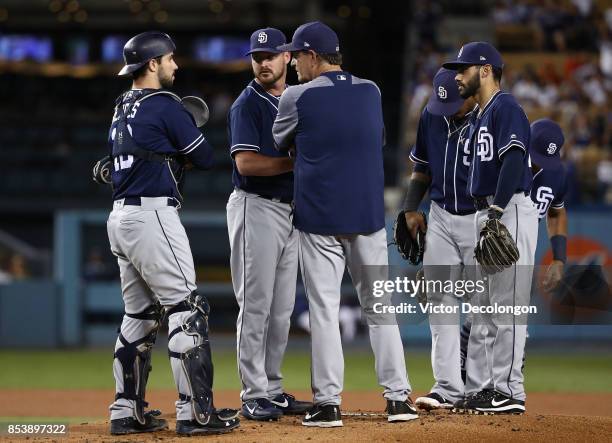 Pitching coach Darren Balsley of the San Diego Padres talks to catcher Austin Hedges and pitcher Travis Wood after loading the bases during the first...