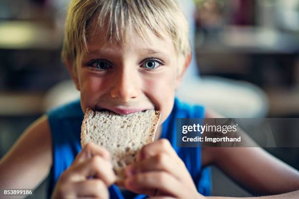 kleine jongen eten van volkoren-roggebrood - broodje voedsel stockfoto's en -beelden