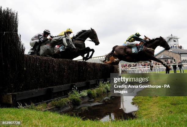 Horses pass over the water jump at Cartmel Racecourse, Cartmel, Cumbria.