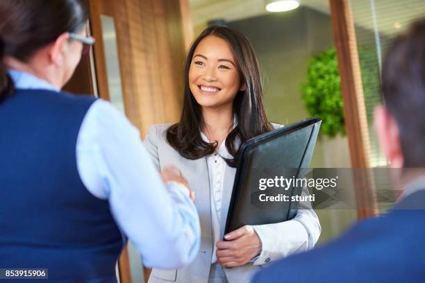 job kandidaat glimlachen als ze het interview binnenkomt - asian shaking hands stockfoto's en -beelden