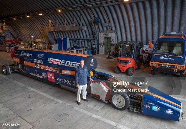 Bloodhound driver Andy Green poses for a photograph besides the Bloodhound Supersonic Car after it was unloaded at its new home in a hanger at...