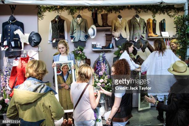 Visitors try-on and purchase clothes at a stall at the Chelsea Flower Show on May 25, 2017 in London, England. The Season in Britain today loosely...