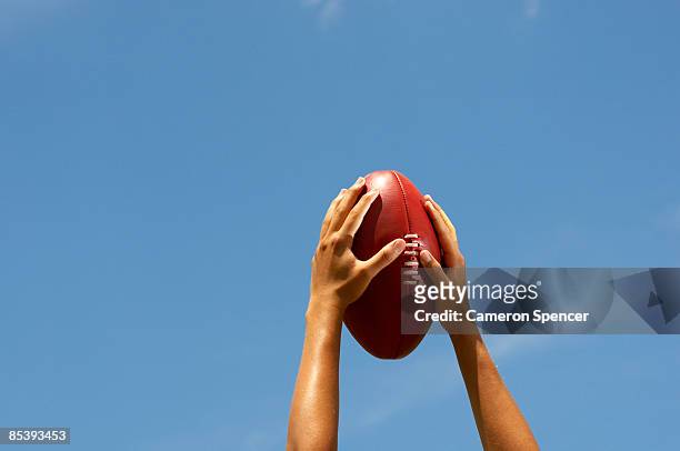hands holding australian football up to the sky - australia soccer ストックフォトと画像
