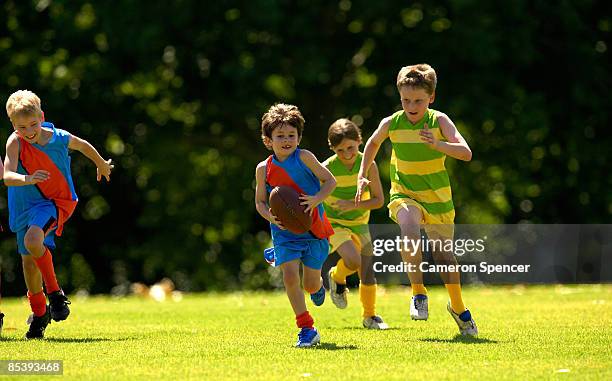 young player running from his opposition - afl australian football league stock pictures, royalty-free photos & images