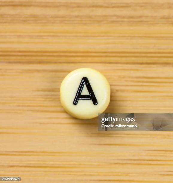 directly above shot of plastic capital letter a on wooden table - buchstabe a stock-fotos und bilder