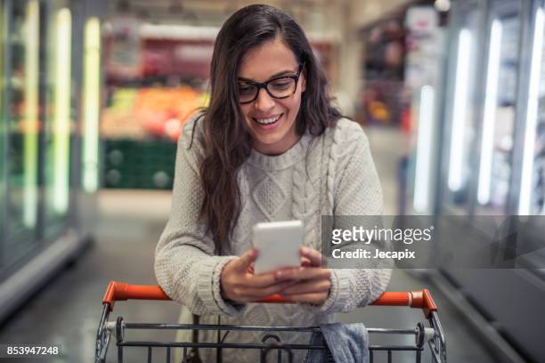 shopping list in the smartphone - young woman trolley stock pictures, royalty-free photos & images