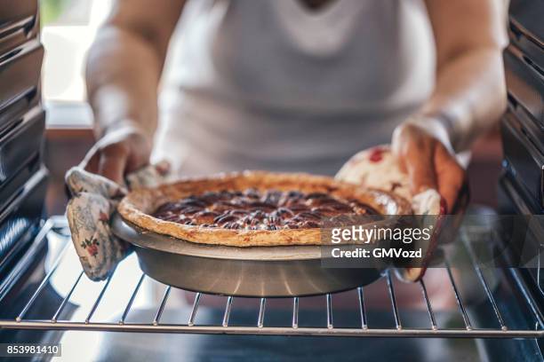 baking pecan pie in the oven for holidays - baking stock pictures, royalty-free photos & images