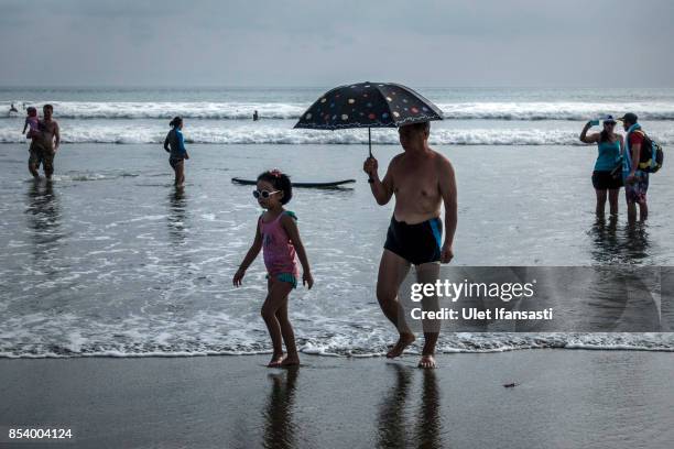 Foreign tourists bathe at Kuta beach on September 26, 2017 in Kuta, Island of Bali, Indonesia. Indonesian authorities raised the alert level for the...