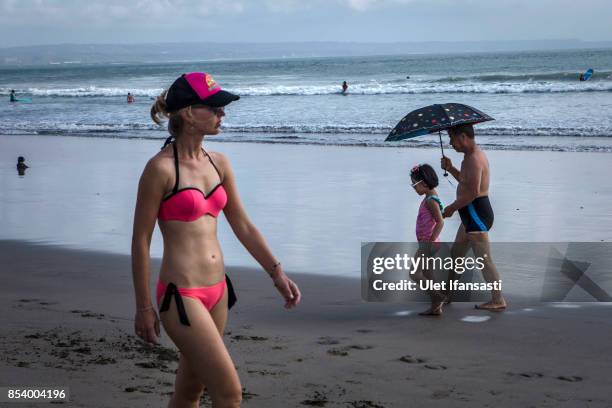 Foreign tourists walk at Kuta beach on September 26, 2017 in Kuta, Island of Bali, Indonesia. Indonesian authorities raised the alert level for the...