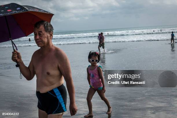 Foreign tourists walk at Kuta beach on September 26, 2017 in Kuta, Island of Bali, Indonesia. Indonesian authorities raised the alert level for the...