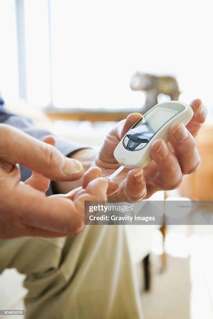 Mature man diabetic testing himself at home