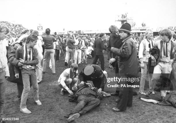 Victim of the Valley Parade football ground fire receives aid on the pitch surrounded by other spectators forced to evacuate the main stand. The...