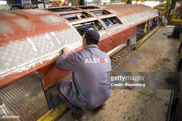 An employee inspects a Reseau Express Regional Paris express train carriage as it stands on the welding assembly line inside the Alstom SA railway...