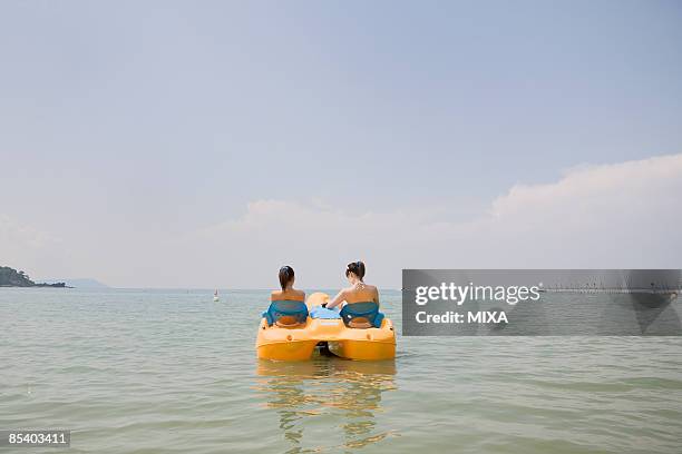 two young women riding on pedal boat - pedal boat foto e immagini stock