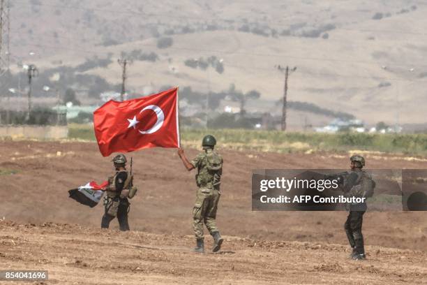 Soldiers holding Turkish and Iraqi flags walk during a joint military exercise near the Turkish-Iraqi border in Sirnak in Silopi district on...