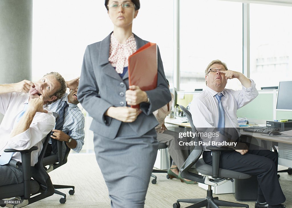 Businesspeople making face at boss in office