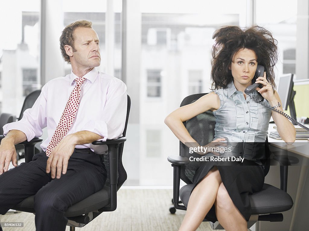 Businessman looking at co-worker talking on telephone