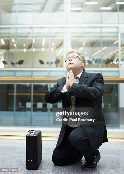 businessman praying in building lobby - hopelessness stockfoto's en -beelden