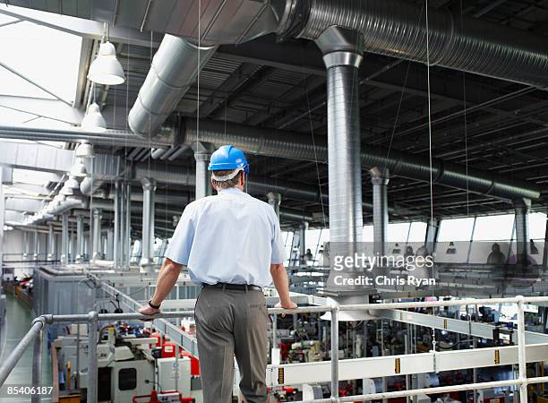hombre de negocios con duro sombrero mirando a la planta de la fábrica - factory fotografías e imágenes de stock