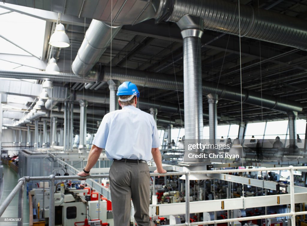Businessman in hard-hat looking at factory floor