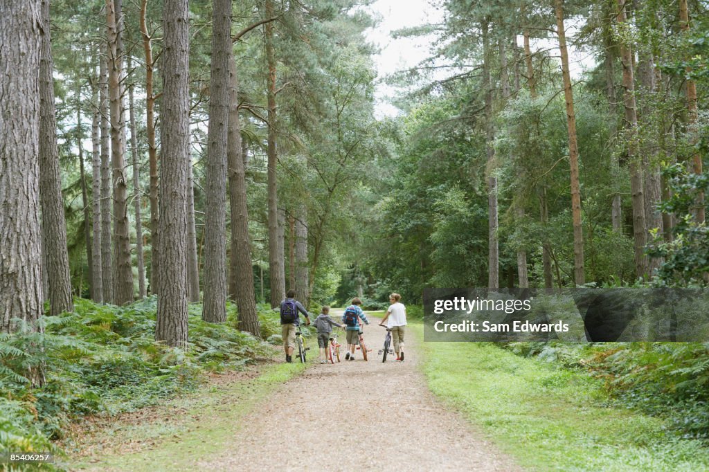 Family walking with bicycles in woods