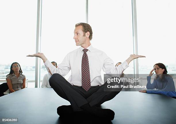 businessman doing yoga in conference room - annoying colleague stock pictures, royalty-free photos & images