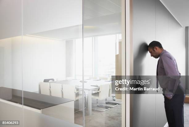 businessman leaning on corridor wall - ongeduldig stockfoto's en -beelden
