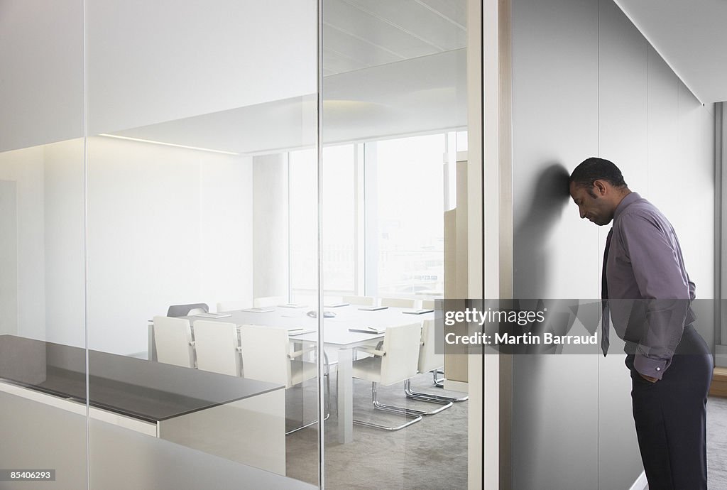 Businessman leaning on corridor wall