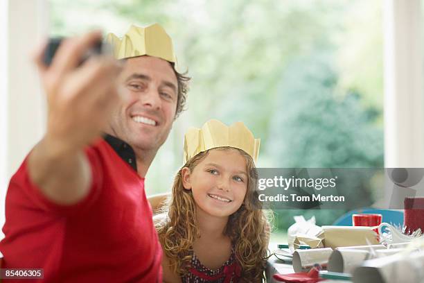 father and daughter in christmas crowns taking self-portrait - paper crown stock pictures, royalty-free photos & images