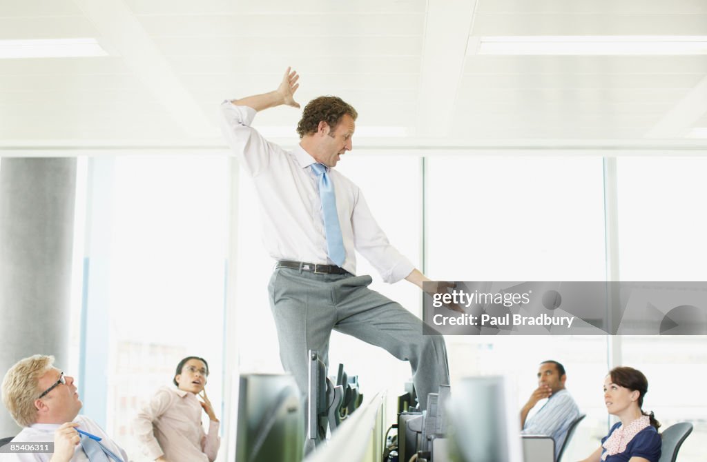 Businessman dancing on desk in cubicle