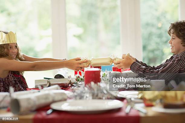 brother and sister tugging christmas cracker - christmas crackers stock pictures, royalty-free photos & images