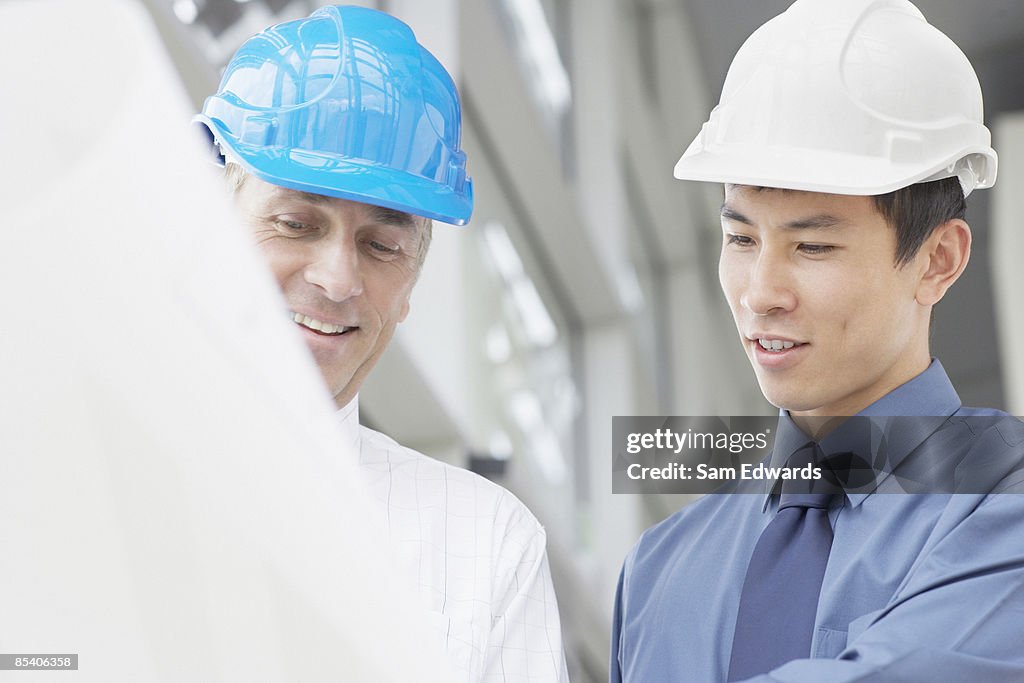 Businessmen in hard-hats looking at blueprints