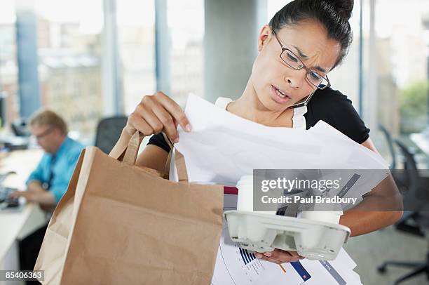 frustrated businesswoman talking on cell phone with paperwork and coffee - multitasking woman stock pictures, royalty-free photos & images