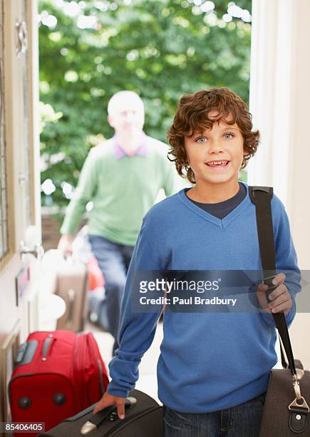 boy carrying luggage - carry on luggage photos et images de collection