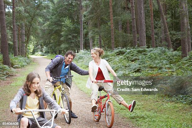 family riding bicycles in woods - 40 49 years stock pictures, royalty-free photos & images