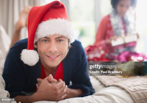 homem postura na cama no chapéu do pai natal - santa hat imagens e fotografias de stock