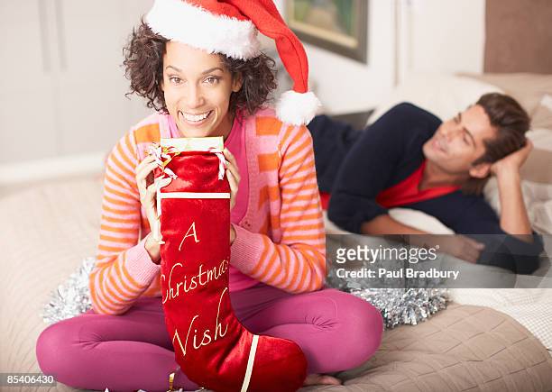 woman holding christmas stocking - black women in stockings stockfoto's en -beelden