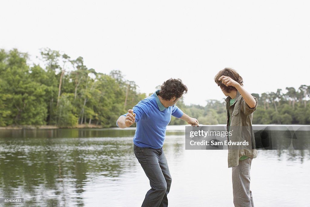 Vater und Sohn Steine hüpfen lassen in lake